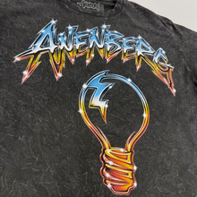 Close-up of the Anenberg Air Guitar Black Crystal Wash Long Sleeve T-Shirt featuring oversized metallic blue and fiery orange-red Anenberg lettering, a retro light bulb graphic with lightning bolt, and sparkling starburst details. Vibrant screen-printed artwork on distressed black and gray crystal wash fabric.