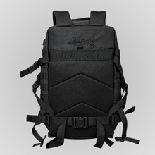 Rear view of the Anenberg Black Out Pack Out Tactical Backpack with shoulder straps folded behind the bag, revealing a breathable black mesh padded back panel with ergonomic cushioning. Black-on-black Anenberg Single Story logo embroidery accents the upper section, while adjustable waist straps, a quick-release buckle, reinforced side webbing, and durable black fabric highlight the tactical-inspired construction. Rugged everyday carry backpack from Southern California streetwear brand Anenberg.