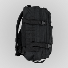 Right side view of the Anenberg Black Out Pack Out Tactical Backpack featuring durable all-black fabric, multiple zippered compartments, horizontal MOLLE webbing loops, and two adjustable compression straps with black quick-release buckles. A mesh side pocket, padded shoulder strap, reinforced stitching, and additional adjustable webbing highlight the rugged, functional design of this tactical-inspired everyday carry backpack from Southern California streetwear brand Anenberg.